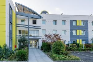 ein Bürogebäude mit gelber und blauer Fassade in der Unterkunft B&B HOTEL Bordeaux Lac sur Bruges in Bruges