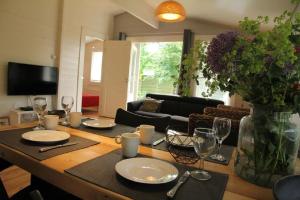 een woonkamer met een tafel met borden en wijnglazen bij Cozy Cottage in Warmenhuizen