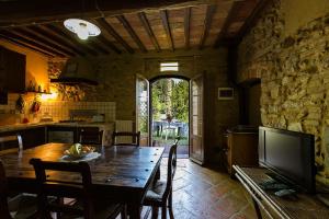 una cucina e una sala da pranzo con tavolo e TV di Rustico in Pietra a Chianni
