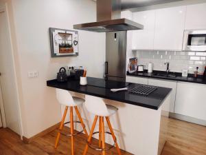 a kitchen with a black counter and two bar stools at Apartamento El Barranco in Seville