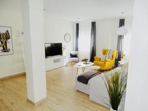 sala de estar blanca con sofá y TV en Apartamento El Barranco en Sevilla