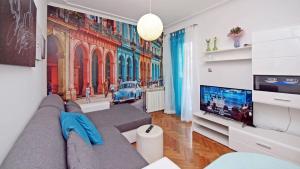 ein Wohnzimmer mit einem grauen Sofa und einem TV in der Unterkunft Apartment Ljubica in Vodice