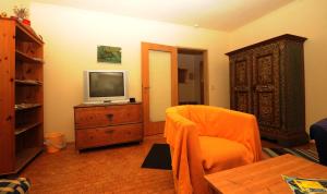 a living room with an orange chair and a television at Kandolf Apartments Klagenfurt in Klagenfurt