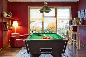 a pool table in a living room with red walls at Campanile Epône in Épône
