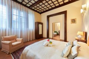 una camera con un grande letto bianco e una sedia di Villa Socini a Siena