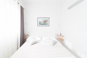 een slaapkamer met witte muren en een bed met witte kussens bij Apartment Seventh Heaven in Podstrana