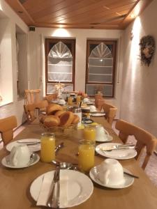 ein Esszimmer mit einem Tisch mit Brot und Gläsern Orangensaft in der Unterkunft Gästehaus Hannelore in Geiselwind