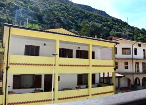 a yellow building with a mountain in the background at Mille Soli Bed and Breakfast in Buggerru