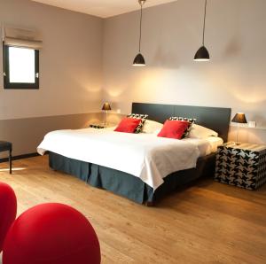 una camera da letto con un grande letto con cuscini rossi di LeCoq-Gadby Hôtel & Spa, The Originals Relais a Rennes