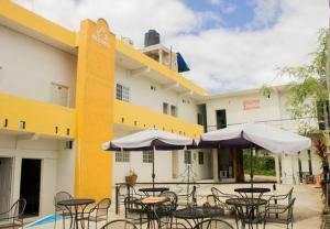 - une vue sur l'extérieur d'un hôtel avec des tables et des parasols dans l'établissement Rosvel Hotel, à Palenque