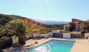 una piscina con una palmera y una casa en Mas Les Romarins, en Montesquieu