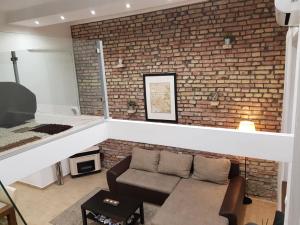 a living room with a brick wall and a couch at Beige & Brown in Budapest