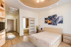 a white bedroom with a bed and a tv at Panorama Apartment in Dnipro