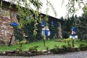 un bâtiment avec des fenêtres bleues et un panneau devant lui dans l'établissement Chambres d'Hôtes Gelous, à Bidache