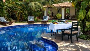 a table and chairs next to a swimming pool at Casa de São José Hotel Boutique in Camocim