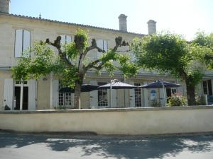 un edificio con árboles y sombrillas delante de él en Hôtel Rapin en Portets