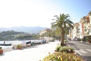 a street with palm trees and boats on the water at The Palm House in Santa Margherita Ligure