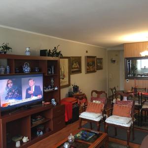 a living room with a flat screen tv and chairs at Frente a Playa - 3 dorms, 2 baños, parking, WiFi, 2 cuadras MALLS in Viña del Mar