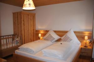 1 dormitorio con 1 cama con sábanas y almohadas blancas en Ferien beim Baur, en Bad Bayersoien
