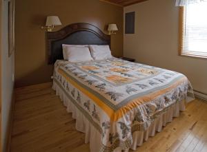 a bedroom with a bed with a quilt on it at Mackenzie Motel & Cottages in Shelburne