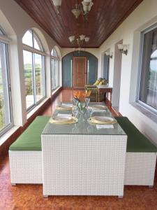 a large room with a table with green cushions and windows at Villa Flor do Monte in Lagoa