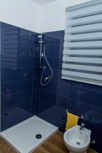 a blue tiled bathroom with a shower and a toilet at Sealand in Nunziata