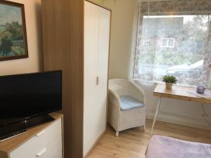 a living room with a television and a chair and a window at Nordsee-Lilie in Wilhelmshaven
