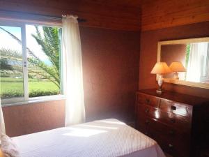 a bedroom with a bed and a window and a dresser at Villa Flor do Monte in Lagoa