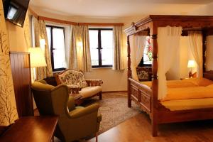 a bedroom with a four poster bed and a chair at Hotel Sonnenhof in Klagenfurt