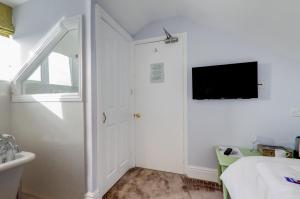 1 dormitorio con 1 cama y TV en la pared en Sunrise Guest House, en Bude