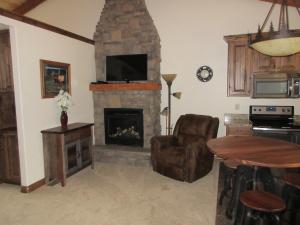 a living room with a stone fireplace with a tv at Townhomes on the Green in Afton