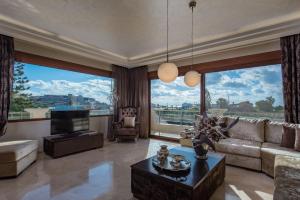 a living room with a couch and a tv and large windows at Callista Luxury Residences in Ierapetra