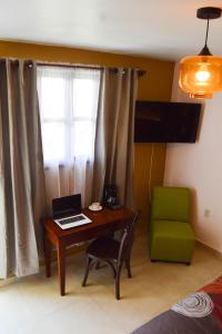 Habitación con escritorio, ordenador portátil y silla verde. en Hotel Las Candelas de Huamantla en Huamantla