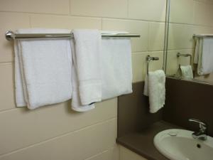 Nambour Lodge Motel في نامبور: حمام به مناشف بيضاء ومغسلة ومرآة