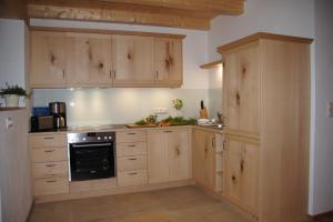 a kitchen with wooden cabinets and a black oven at Ferien beim Baur in Bayersoien