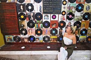 a woman sitting on a bench in front of a wall of records at Hotel Mary Carmen in Cozumel