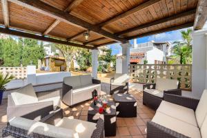 a patio with white furniture and a wooden pergola at Villa Can Giovanni in Sant Jordi