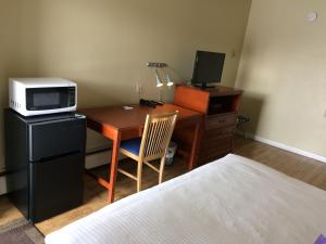 Schlafzimmer mit einem Schreibtisch, einer Mikrowelle und einem Bett in der Unterkunft Nice Inn Edmonton in Edmonton