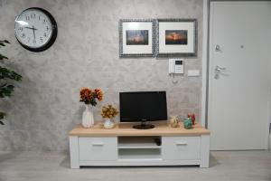 a room with a tv on a desk with a clock at Ericeira Holiday House - Centre of the Village in Ericeira