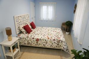 um pequeno quarto com uma cama com almofadas vermelhas em Ericeira Holiday House - Centre of the Village na Ericeira