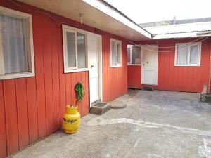 a red house with a yellow vase next to a building at Cabañas Holtheuer in Valdivia