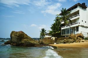 a white building on the beach next to the ocean at La Veranda Di Serena in Unawatuna