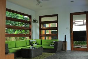 sala de estar con sofá verde y TV en Papillon Umalas Villas, en Canggu