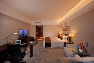 a hotel room with a bed and a living room at Kunshan International Hotel in Kunshan