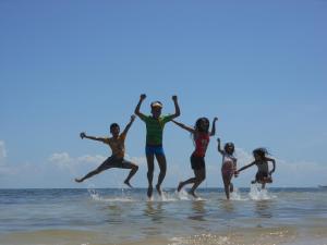 a group of people jumping in the water at the beach at La Villa Alta in Siquijor