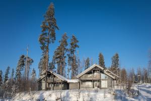 een blokhut in de sneeuw met bomen bij Pyry ja Tuisku Cottages in Muurame