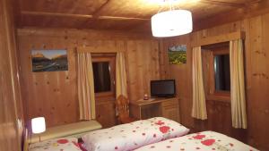 a bedroom with two beds and a television in it at Lüch dl Chessl - Kesslhof in San Martino in Badia