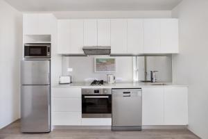 uma cozinha com armários brancos e electrodomésticos de aço inoxidável em Bondi Beach Studio Penthouse Suite + Balcony em Sydney