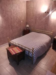 1 dormitorio con cama con colcha a rayas y mesa en Maisonnette de Villiers en Saint-Fargeau-Ponthierry