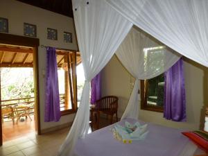 a bedroom with a canopy bed with purple curtains at Sananda Bungalow in Lovina